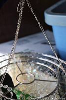 Metal frame with hanging chain attached, showing circular structure.