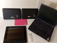 Overview showing Dell Latitude laptop and four tablets, including two black Proscan PLT1066G tablets, one smaller pink tablet, and one larger black tablet
