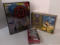 Lot showing all three items: 500-piece puzzle box, "Cars" domino metal tin, and "Game Night" magnetic dart game box with darts and tray.
