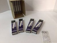 The box and eight boxed lamps lined up plus an information card describing the lot.