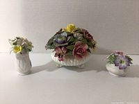 Wide shot showing all three porcelain floral decor pieces of different sizes and styles