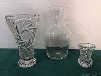 Front view of three crystal vases: large Luminarc vase with patterned rim, medium clear vase, and small star-cut patterned vase