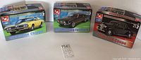 Three AMT brand new car model kits side by side: 1971 Dodge Charger, 1967 Mustang Fastback, 1936 Ford Coupe.