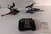 Photo showing both helicopters and the remote control on white surface under neutral lighting.