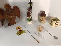 Overall view of the wooden eagle clock, ceramic music box, ceramic cider jug, necklaces, small decorative items, and vintage plastic box.