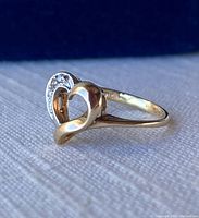 Close-up side view of 10K gold heart ring with part diamond accents showing polished gold band.