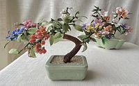 Photo showing larger glass bonsai tree with multiple colored flowers and leaves in green ceramic pot