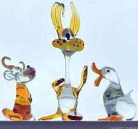 Photo showing side view of three handblown glass figurines: rabbit in center taller than cow on left and duck on right