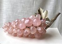 Side view of rose quartz grape cluster with pink translucent stones, metal stem and leaves