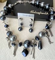 Necklace and earrings set displayed on a black Shepherd's box showing the design and arrangement of beads and tassels clearly.