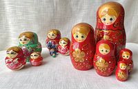 All three sets of nesting dolls arranged in groups by set on linen background