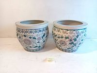 Front view of two ceramic planters showing floral and geometric designs