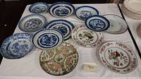 All 11 plates arranged on table showing variety of blue and white and colorful designs.