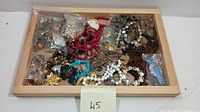 View of various costume jewelry pieces including necklaces, bracelets, rings, and brooches in wooden tray (tray not included).