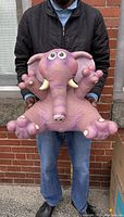 Photo of person holding large purple rubber elephant plush sculpture with large eyes and tusks