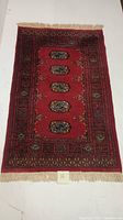 Full view of the hand knotted Indo Bokhara area rug with red base and medallion design.