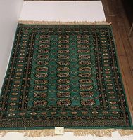 Full view of teal Indo Bokhara area rug showing overall design and fringes.
