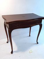 Full view of vintage wooden game table showing curved top and cabriole legs