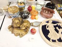 Table display of ceramic pottery pieces including ceramic wall plaques of Cupids, assorted artisan bowls, and Fiesta salt shakers in multiple colors.