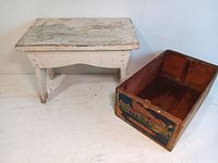 Photo showing the worn white wooden step stool alongside the advertising box with colorful painted design
