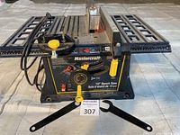 Front view of the Mastercraft 10 inch bench saw on a light gray surface with a MaxSold auction tag in front and two adjustment wrenches laid out.