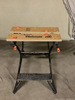 Front view of Black & Decker Workmate 200 workbench showing wooden top with orange adjustments and metal frame.