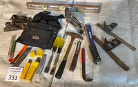 Full assortment of carpentry hand tools arranged on cloth: block planes, claw hammers, chisels, handsaw, level, utility knife, square tools, and tool pouch.
