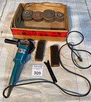 Complete lot with Makita grinder, grinding disks in box, wire brushes, and wrench
