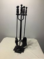 Front view of the fireplace tool set including the stand and four tools with round handles.