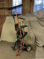 Full view of the garden cart loaded with various gardening tools including rakes, shovels and a leaf stamper.