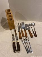 Photo showing the full lot of utensils and wooden block, including various knives, forks, spoons, and the block