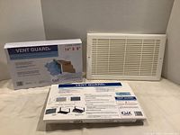 White rectangular vent guard grille alongside the box showing four replacement filters.