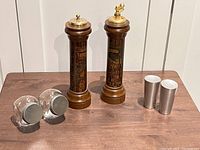 Wide shot of all six items: two Italian wooden salt and pepper mills, two small glass spice jars, and two metal spice shakers.