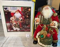 Photo showing Santa Claus figurine seated on chair next to original white storage box with packaging image and text