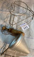 Photo of metal tripod stand, wooden pestle, and aluminum strainer sieve showing the lot items together