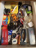 Drawer with assorted hand tools including scissors, pliers, screwdrivers, voltage tester, plug-in night lights, and 23 piece bit and socket set case.