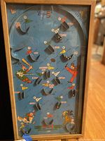 Full view of the pinball game playfield showing cartoon sports characters, metal pins, and point scoring areas.