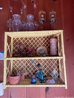 Full frontal shot of vintage bamboo shelf hosting various decorative items as per lot description.