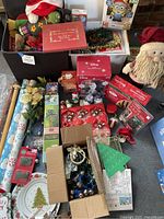 Overview of various Christmas decor items including lawn inflatables, dishes, Disney Olaf boxes, and small decorations spread on the floor