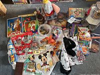 Photo showing various Disney themed items including puzzles, small toys, figurines, and plush. Large pile of DVDs in background.