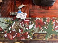 Overview photo of stained glass panel with hummingbird and flowers laid flat beside the brass hummingbird water spigot.