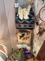 Full view of three Native American style woven blankets displayed on natural pine ladder stand with pillows below and dreamcatcher on wall
