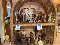 Two shelves of a wicker shelf unit holding Native American books, figurines, pottery, and small collectibles arranged together.