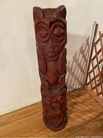 Front view of the wooden totem sculpture showing detailed carving of animal and human faces.