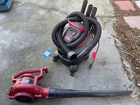 Photo of commercial shop vac with coiled hoses on top on concrete floor outdoors