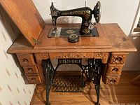 Front angle showing the complete Singer sewing machine set in original wood table with drawers and cast iron treadle base.