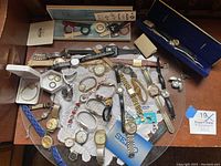 Overhead view of entire assortment of wristwatches, bands, and parts on a tray