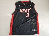 Front view of the black Miami Heat basketball jersey with red accents, number 3 and HEAT logo.