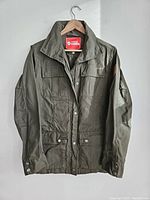 Front view of the olive green Fjallraven jacket showing snap buttons, collar, and pockets