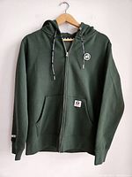Front view of olive green zip-up hoodie on hanger